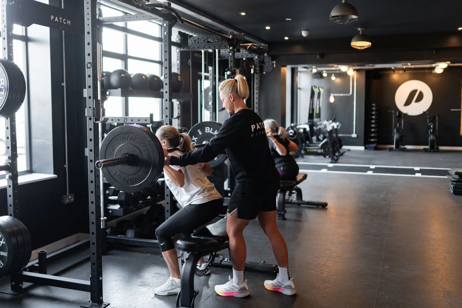 A coach guiding a member at the rack