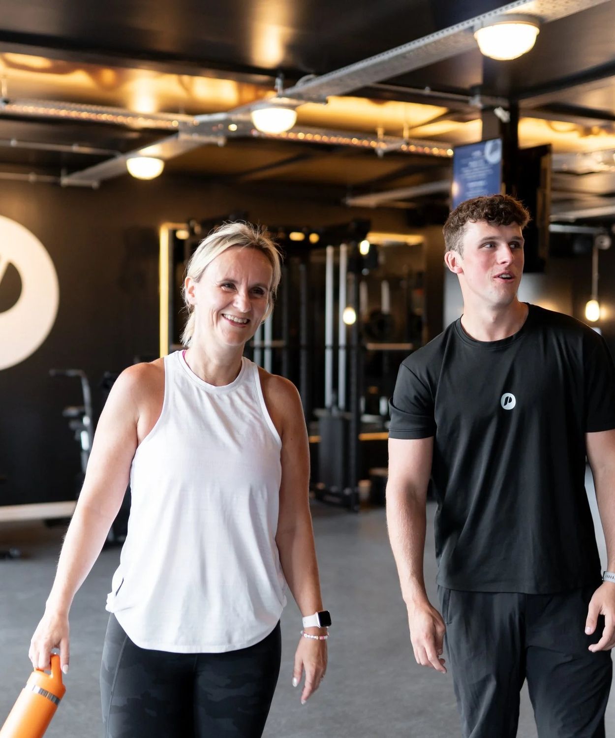 A Patch coach and a member walking across the gym floor, smiling, the Patch logo on the wall behind
